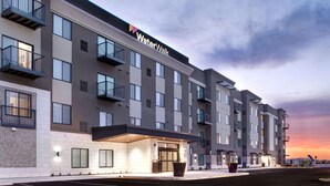 Een hotel met meerdere verdiepingen, met een modern ontwerp, balkons en een opvallende entree.