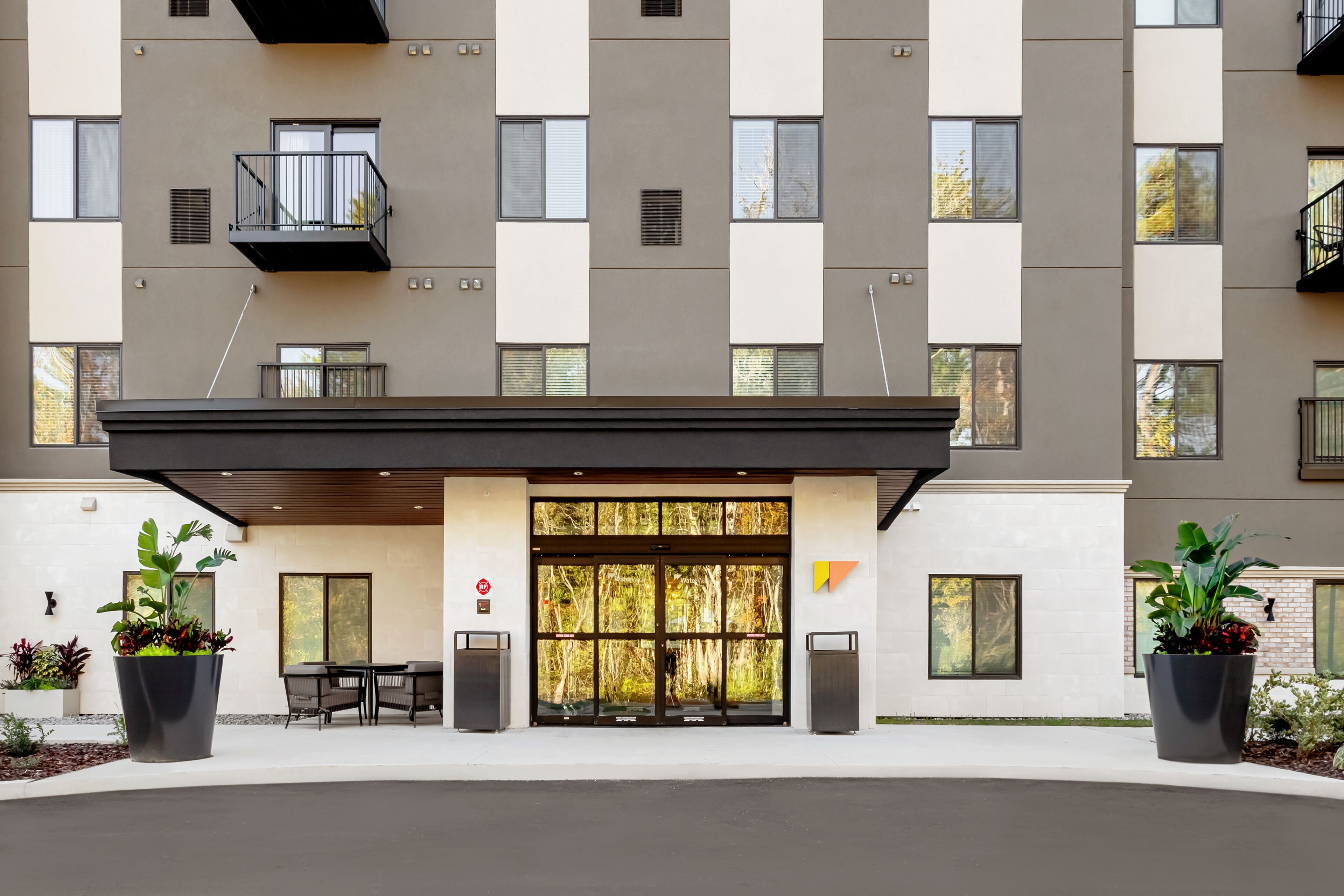 A modern building with a flat facade, large windows, and a covered entrance.
