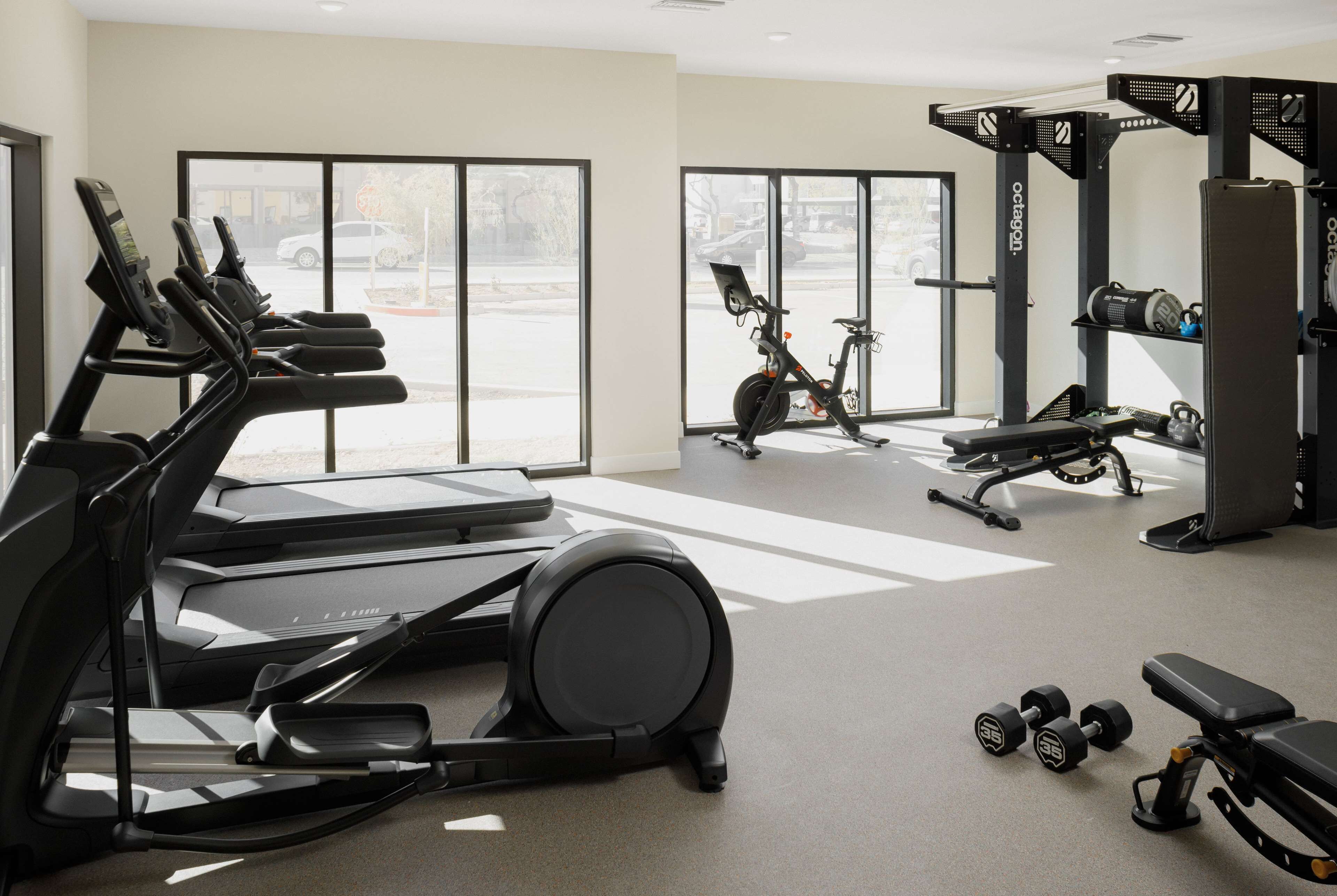 A gym with treadmills, an elliptical, dumbbells, and weight machines.