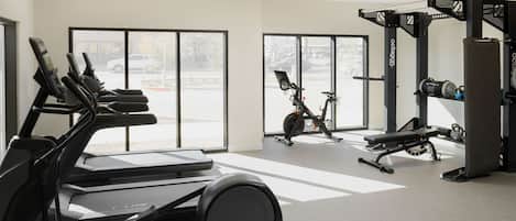 A gym with treadmills, an elliptical, dumbbells, and weight machines.