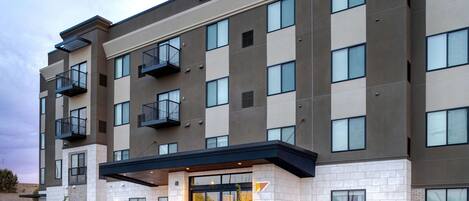 A modern hotel with a flat facade, large windows, and a prominent entrance.
