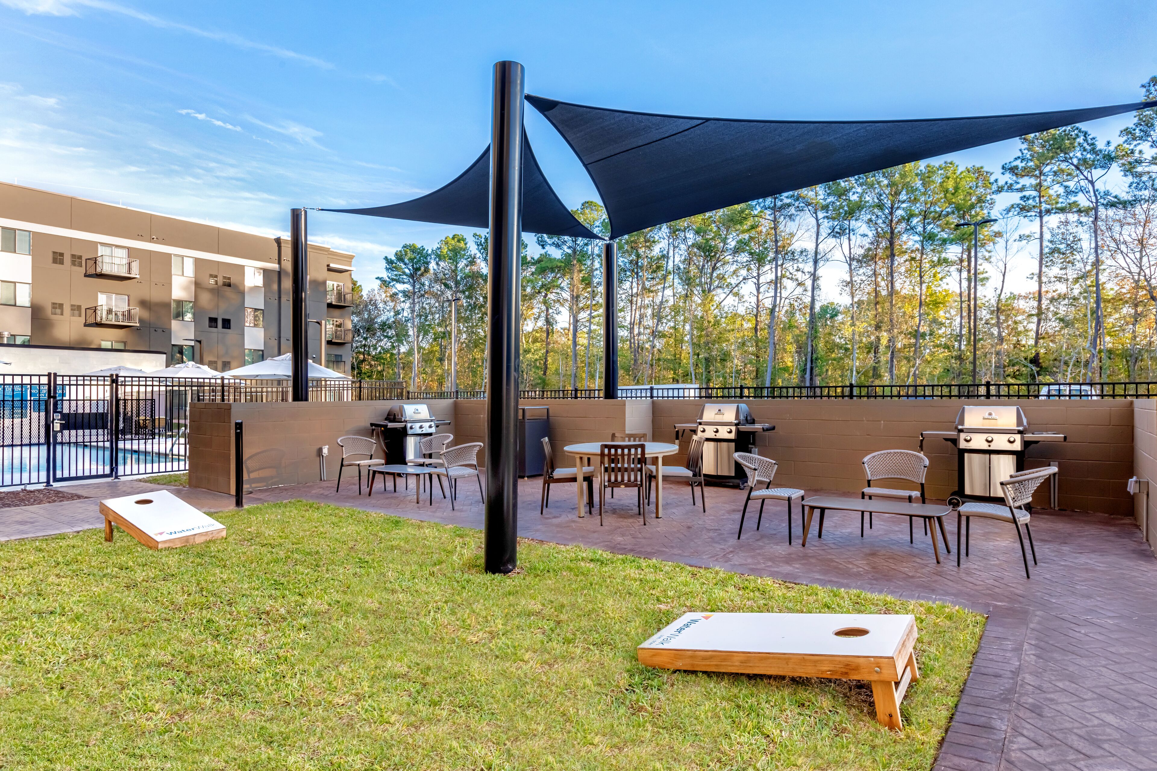 An outdoor patio area with a barbecue grill, seating, and a shaded area.
