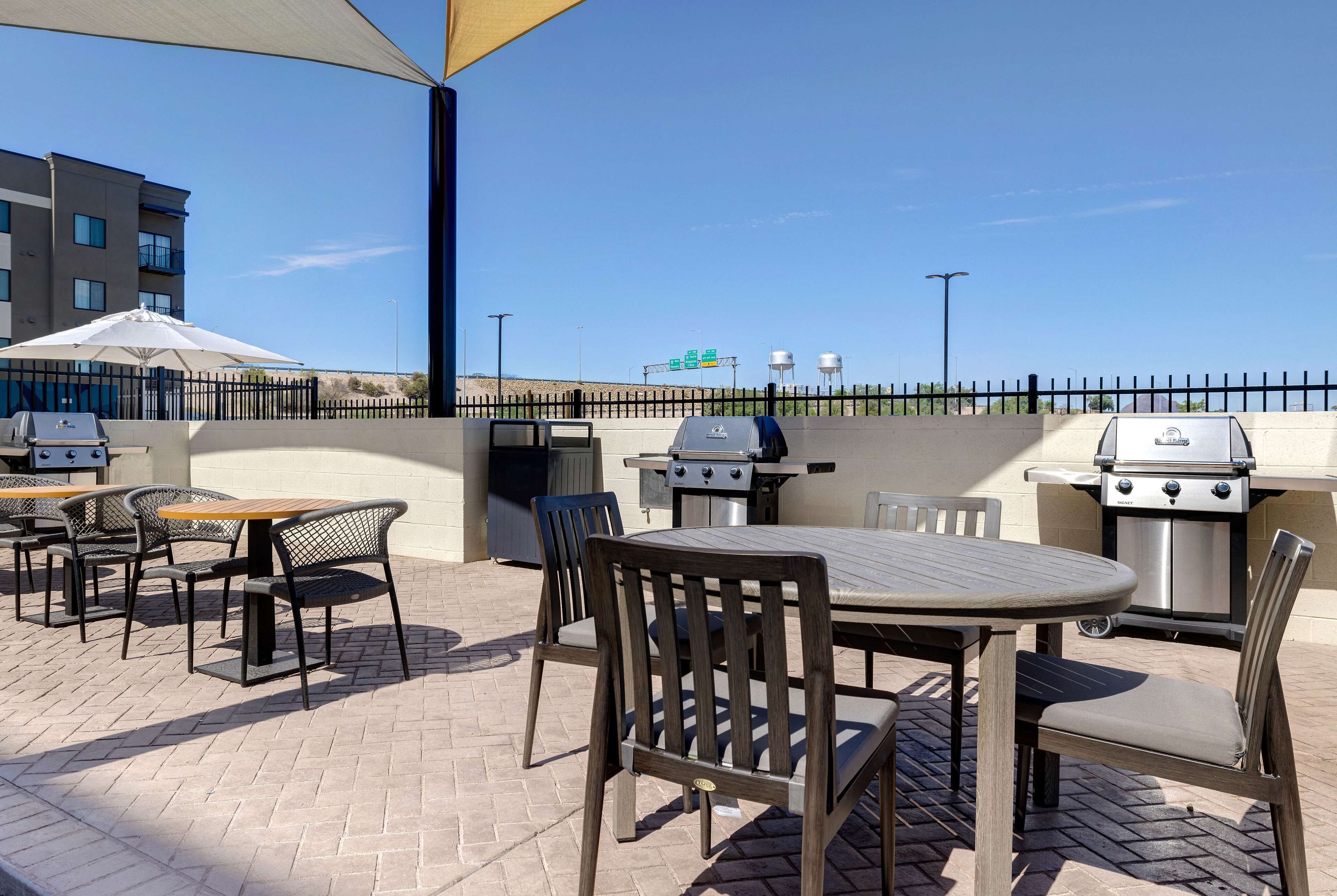 Eine Terrasse im Freien mit Tisch, Stühlen, einem Grill und einem Zaun.