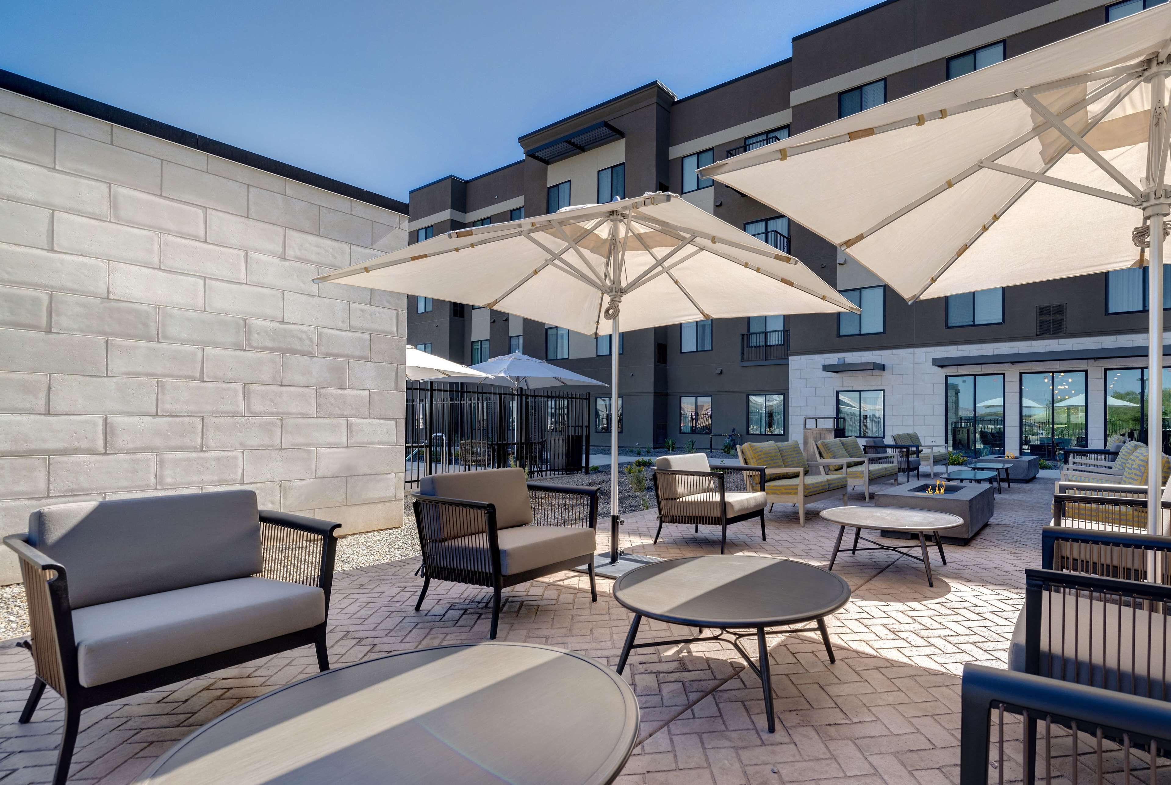 Un espace extérieur aménagé en terrasse, avec des coins salon comprenant des canapés et des tables, le tout protégé par de grands parasols.