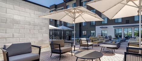 An outdoor patio area with seating arrangements, including sofas and tables, under large umbrellas.