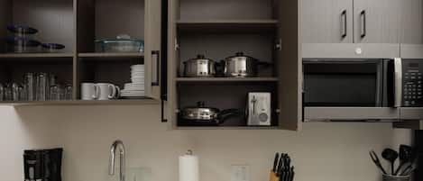 A modern kitchen with stainless steel appliances, a coffee maker, and neatly organized utensils.
