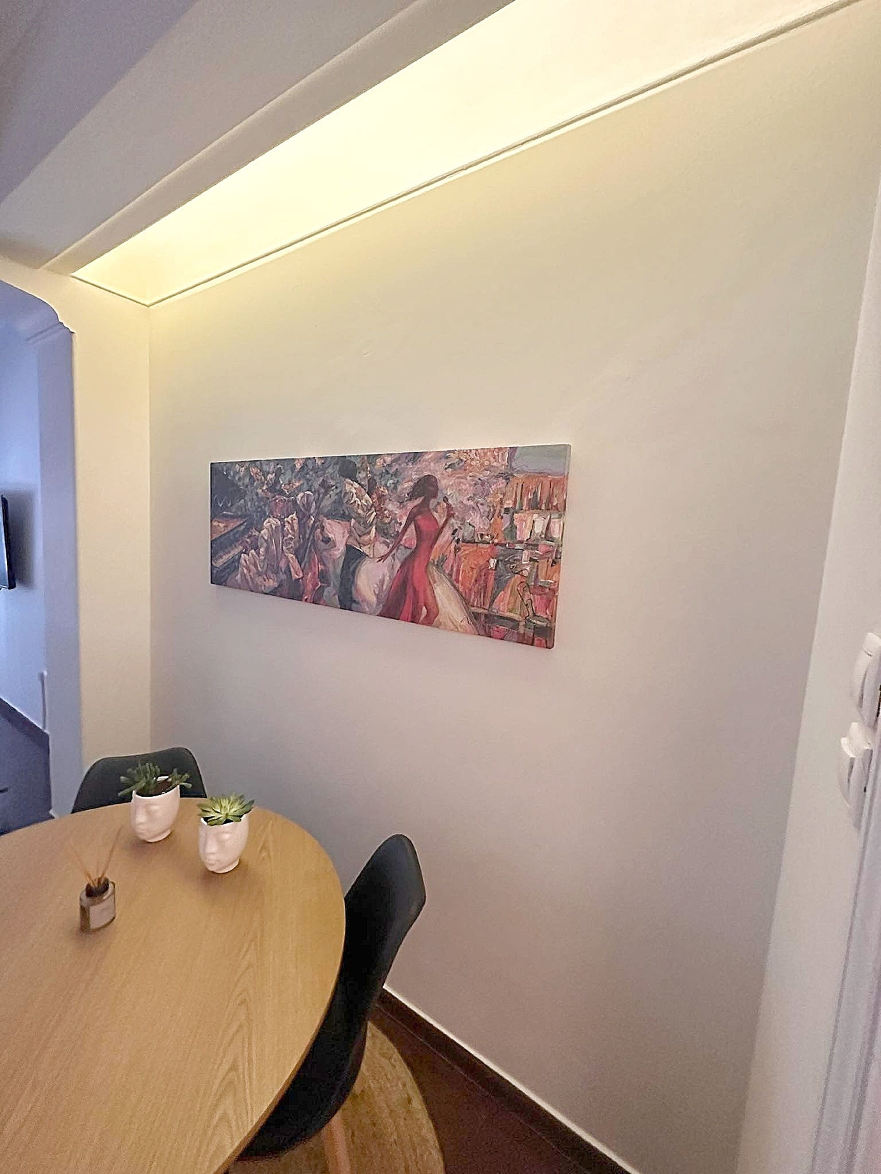 Een vergaderruimte met een ronde tafel, twee potplanten en een groot abstract schilderij aan de muur.