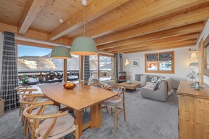 A cozy, wood-paneled room with a dining area, sofa, and a fireplace. - Chalet Sapin Argenté (Riddes)