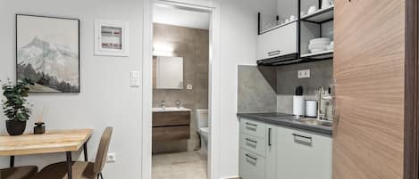 Una cocina moderna con armarios grises, una mesa de comedor de madera y una planta en maceta.