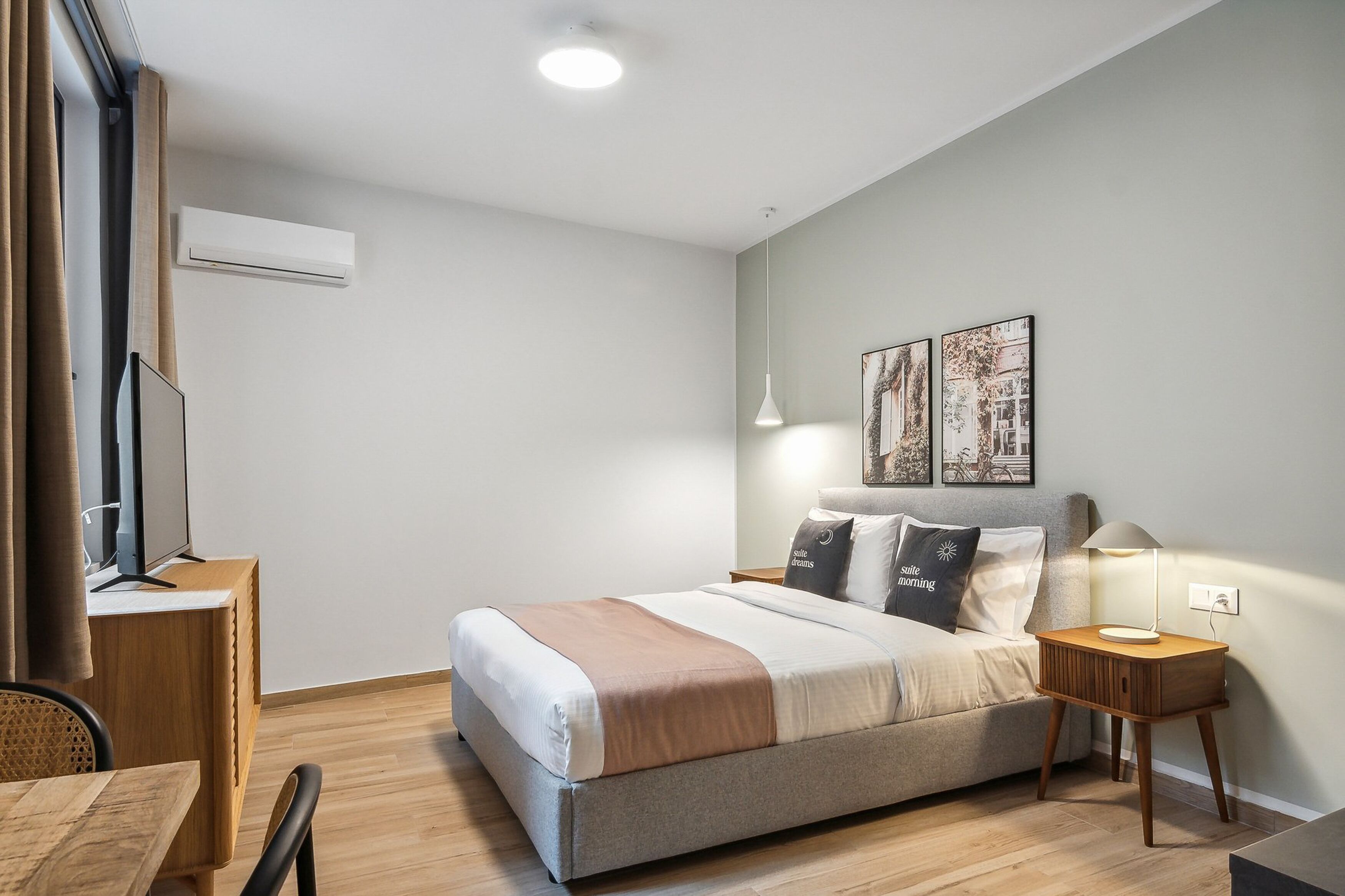 Quarto moderno com cama, mesa de cabeceira, abajur e obra de arte na parede.