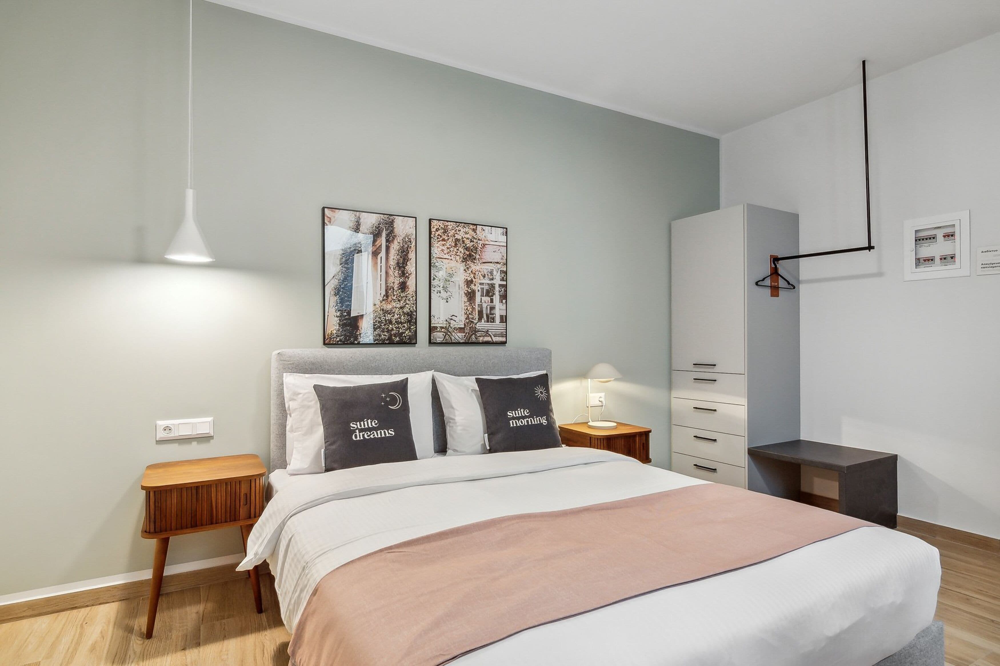 A modern bedroom with a bed, bedside tables, a wardrobe, and wall-mounted artwork.
