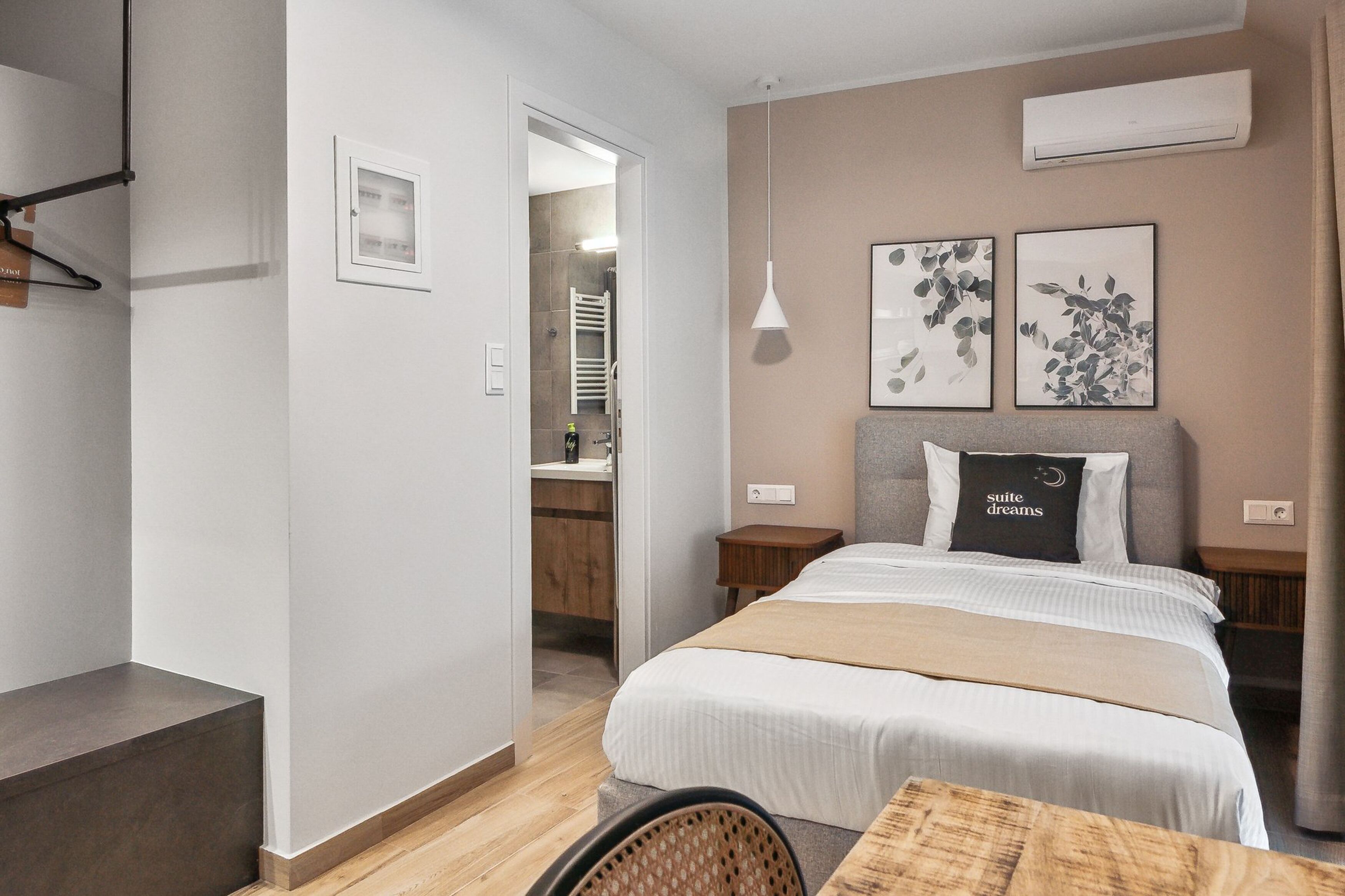 A modern hotel room with a large bed, a bedside table, a chair, and a small table.