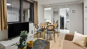 A modern living room with a flat-screen TV, a dining table with chairs, a sofa, and a coffee table. - Limehome Athens Solonos City Center (Athens)