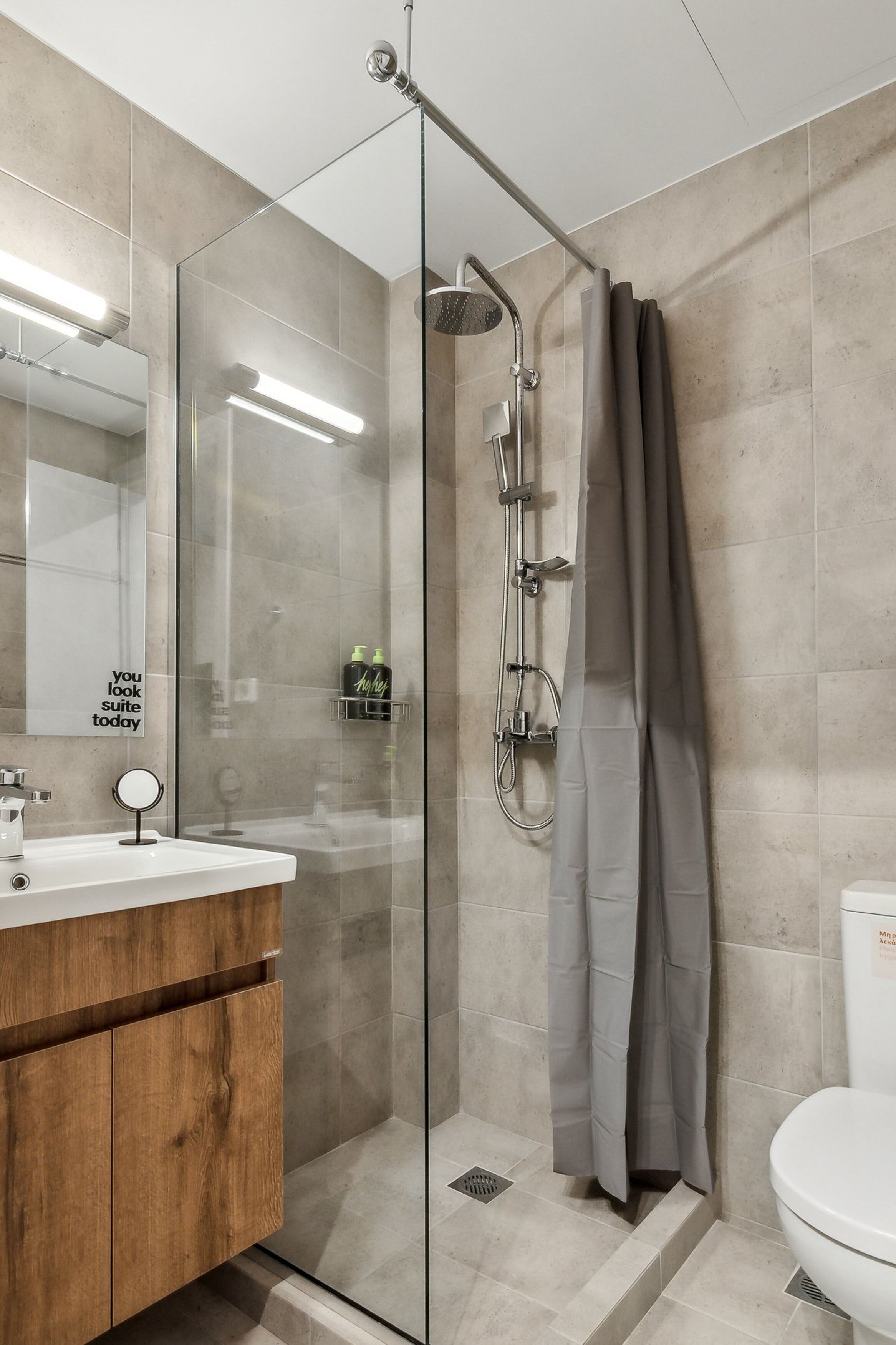 A modern bathroom with a glass-enclosed shower, a wooden vanity, and a large mirror.