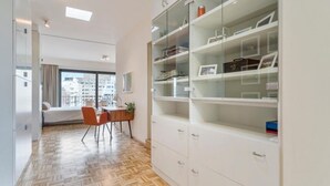Un apartament modern amb un ampli espai obert de sala d'estar, zona de menjador amb taula i cadires, i una biblioteca amb portes de vidre.