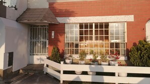 A house with a red brick exterior, a white fence, and a window with multiple panes. - Beautiful beachfront apartment a few minutes from the best Limeña beaches (Ciudad de Guatemala)