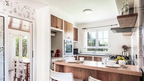 Eine moderne Küche mit Holzschränken, einer zentralen Kochinsel und einem Essbereich mit weißen Stühlen.