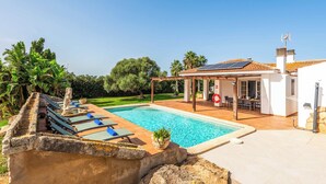 Ein Schwimmbecken mit Liegestühlen, einer Pergola und einer überdachten Terrasse.