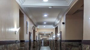 A long, narrow hallway with marble walls and a tiled floor, leading to a door at the end. - CASONI INTERNATIONAL HOTELS AND SUITES (Port Harcourt)