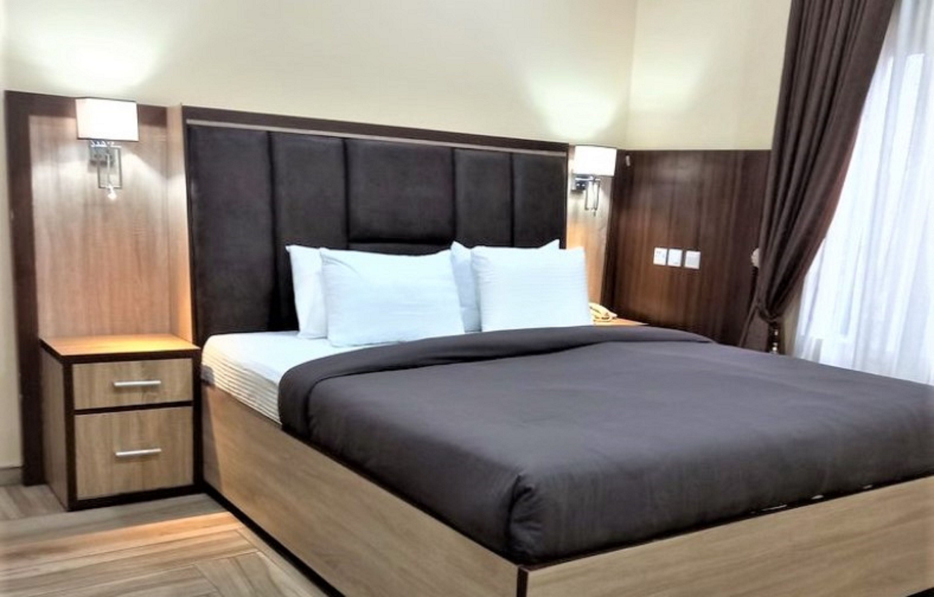 A hotel room with a bed, bedside tables, and a headboard.