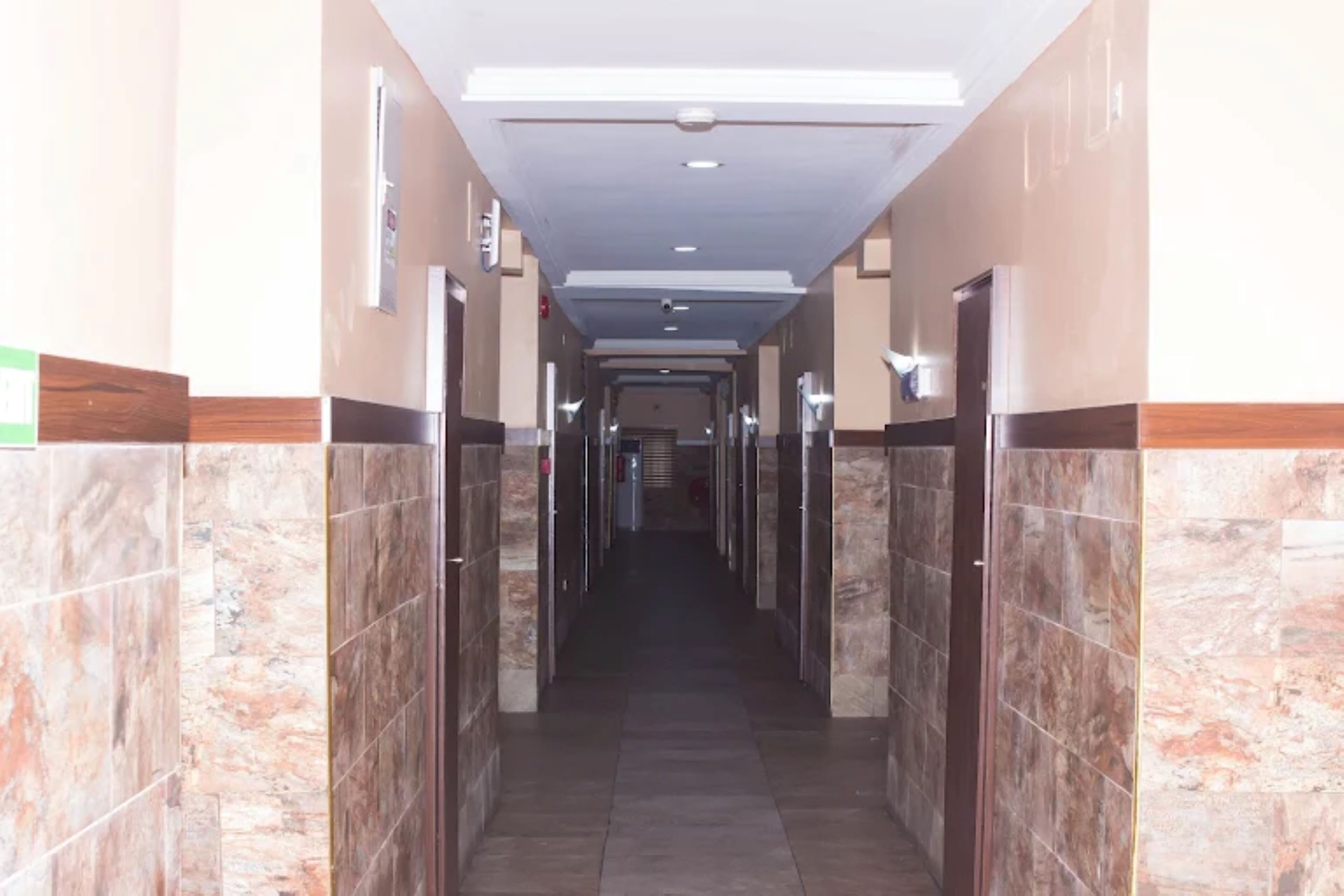 Un pasillo con paredes y puertas de mármol que conduce a una escalera.