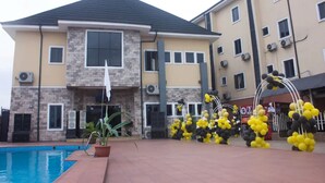 A multi-story hotel with a swimming pool, stone facade, and balconies. - CASONI INTERNATIONAL HOTELS AND SUITES (Port Harcourt)