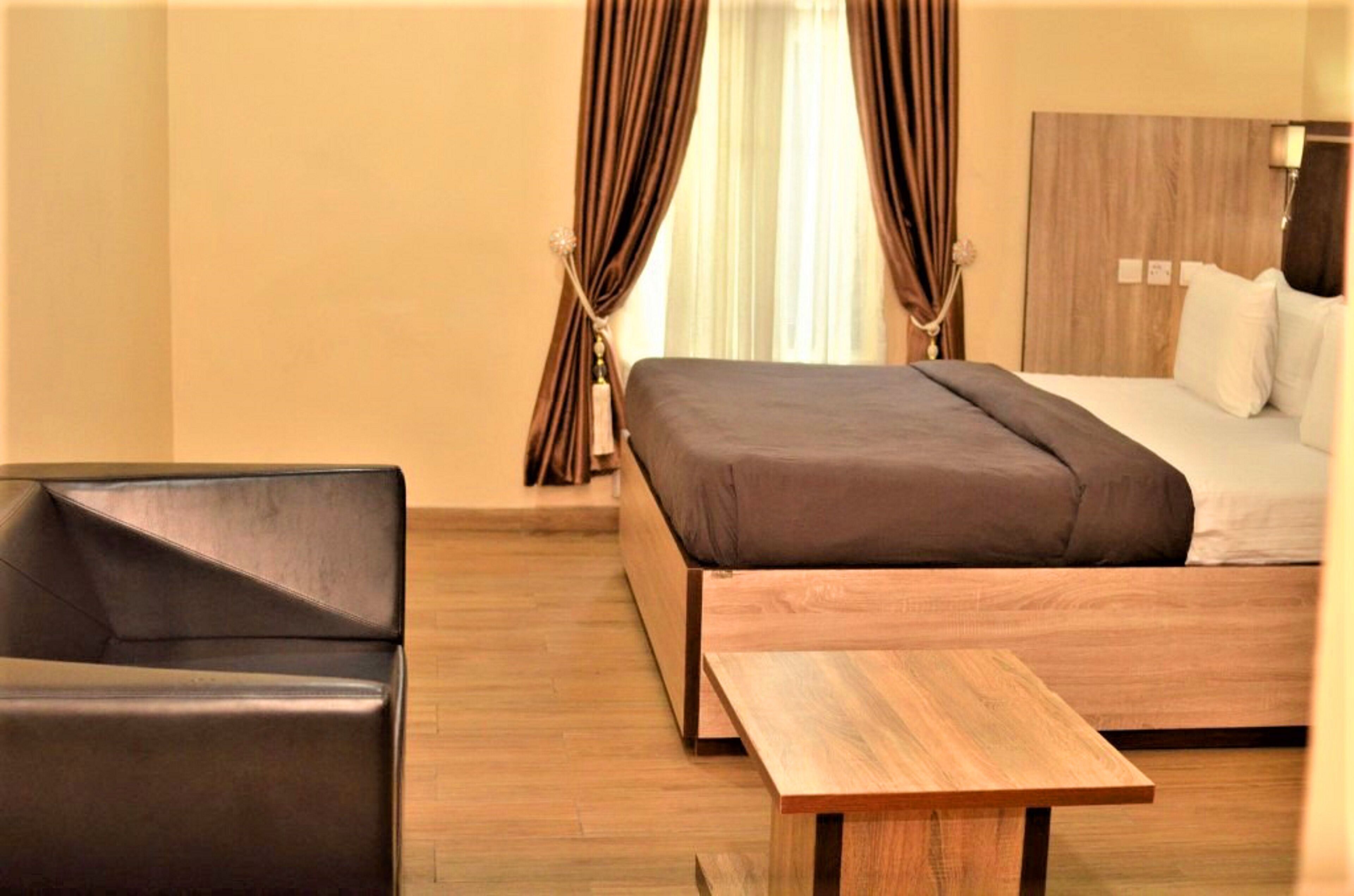 Een moderne hotelkamer met een houten bed, een klein houten tafeltje en een leren fauteuil.