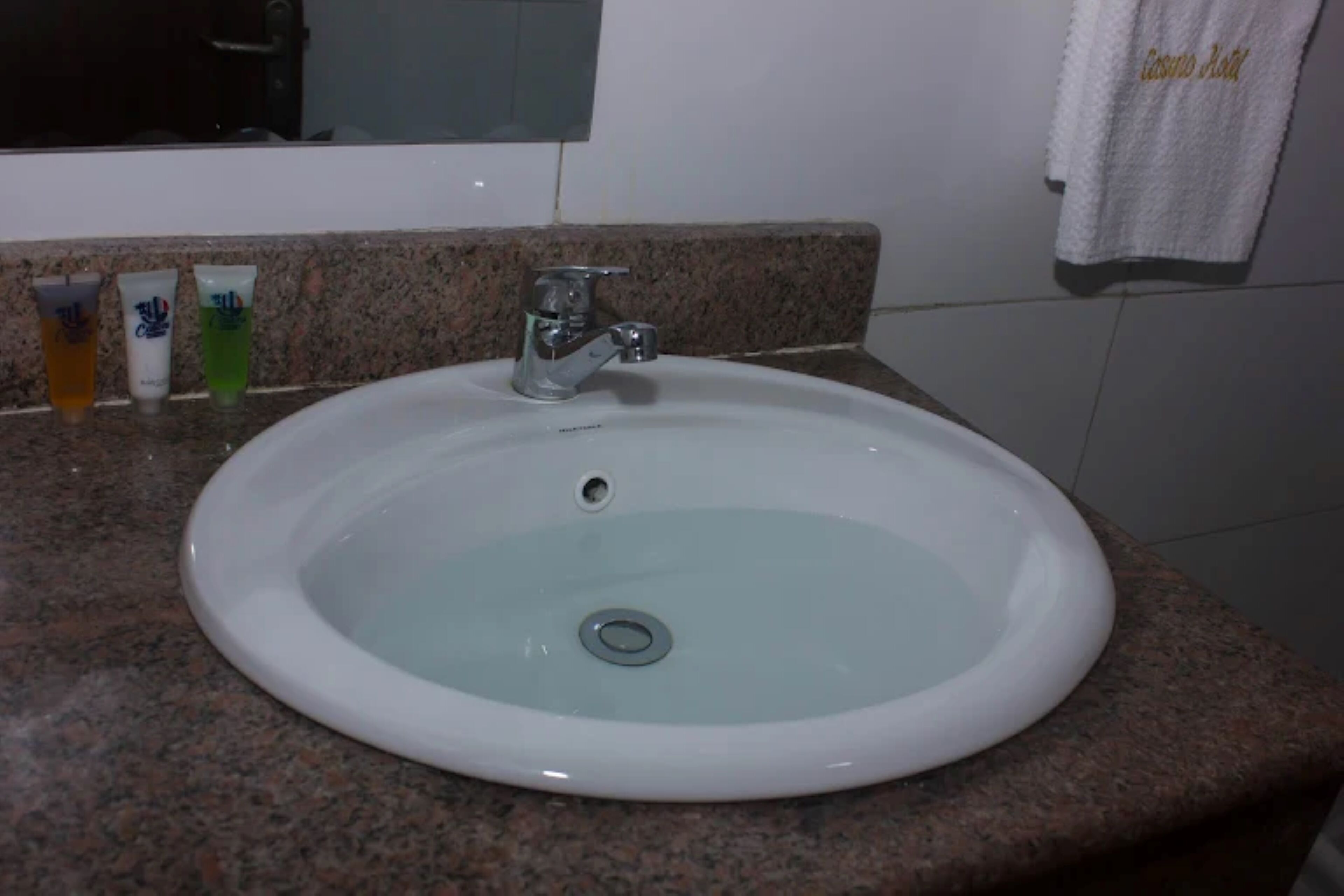 A white sink with a single faucet on a granite countertop.