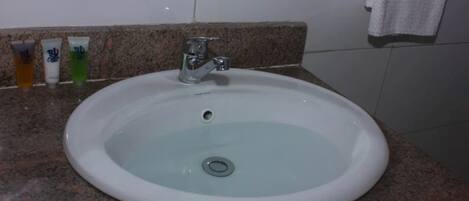 A white sink with a single faucet on a granite countertop.