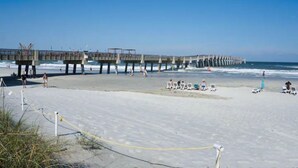 A beach with a pier extending into the ocean, featuring a walkway and seating areas. - Ocean Seaside Escape B
 (Jacksonville Beach)