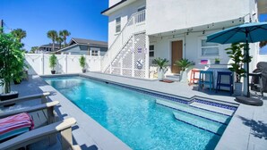 A swimming pool with a white fence, lounge chairs, and a patio area with outdoor furniture. - Ocean Seaside Escape B
 (Jacksonville Beach)