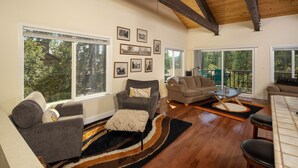 A spacious living room with large windows, a high wooden ceiling, and a cozy seating area with a coffee table. - Dollar Hill II # 25 by Hauserman Rental Group (Tahoe City)