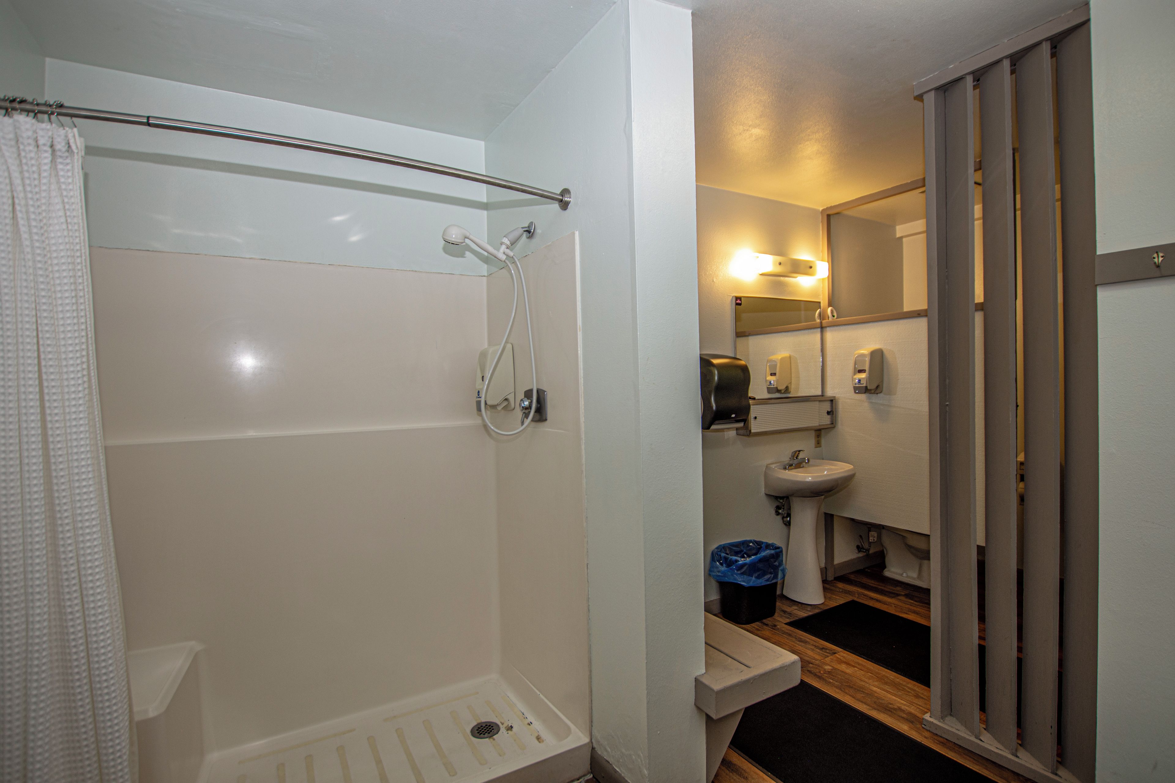 Un baño con ducha, inodoro, lavabo y espejo.