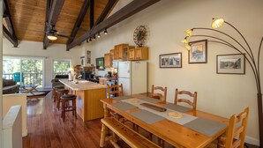 A spacious kitchen with wooden cabinetry, a central island, and a dining area with a wooden table and benches. - Dollar Hill II # 25 by Hauserman Rental Group (Tahoe City)