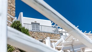Un bâtiment blanc avec un mur en pierre et un balcon doté de rampes en métal.