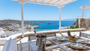 Une table dressée pour le dîner, avec vue sur la mer et une ville côtière.