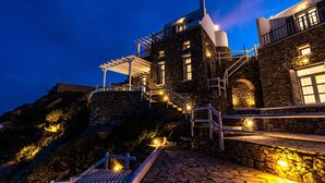 A stone building with a staircase leading to a balcony, illuminated by warm lights. - Luxury VillaThelgoMykonos IV, amazing sea View! (Mykonos)