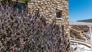 A stone building with a white porch and a view of a mountainous landscape. - Luxury VillaThelgoMykonos IV, amazing sea View! (Mykonos)