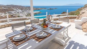 A table set for dining with a view of the sea and town. - Luxury VillaThelgoMykonos IV, amazing sea View! (Mykonos)
