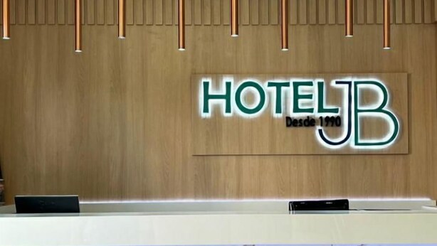 A hotel reception desk with a wooden panel wall and a marble-tiled counter. - Bom Despacho (Bom Despacho)