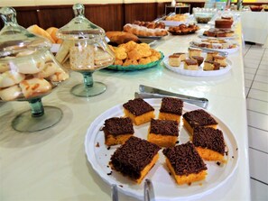A buffet table with various food items including cakes, pastries, and desserts.