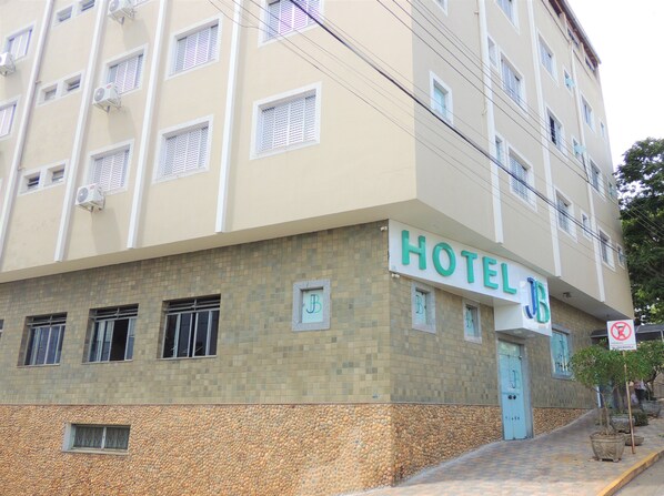 A hotel building with a tiled facade, multiple windows, and a sign indicating the name 'HOTEL JB'.