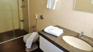 A bathroom with a glass-enclosed shower, a toilet, and a sink with a granite countertop. - Bom Despacho (Bom Despacho)