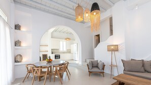 Un interior moderno con zona de comedor, sofá y lámpara de pie.