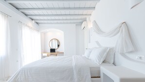 Un dormitorio blanco con cama, escritorio y silla.