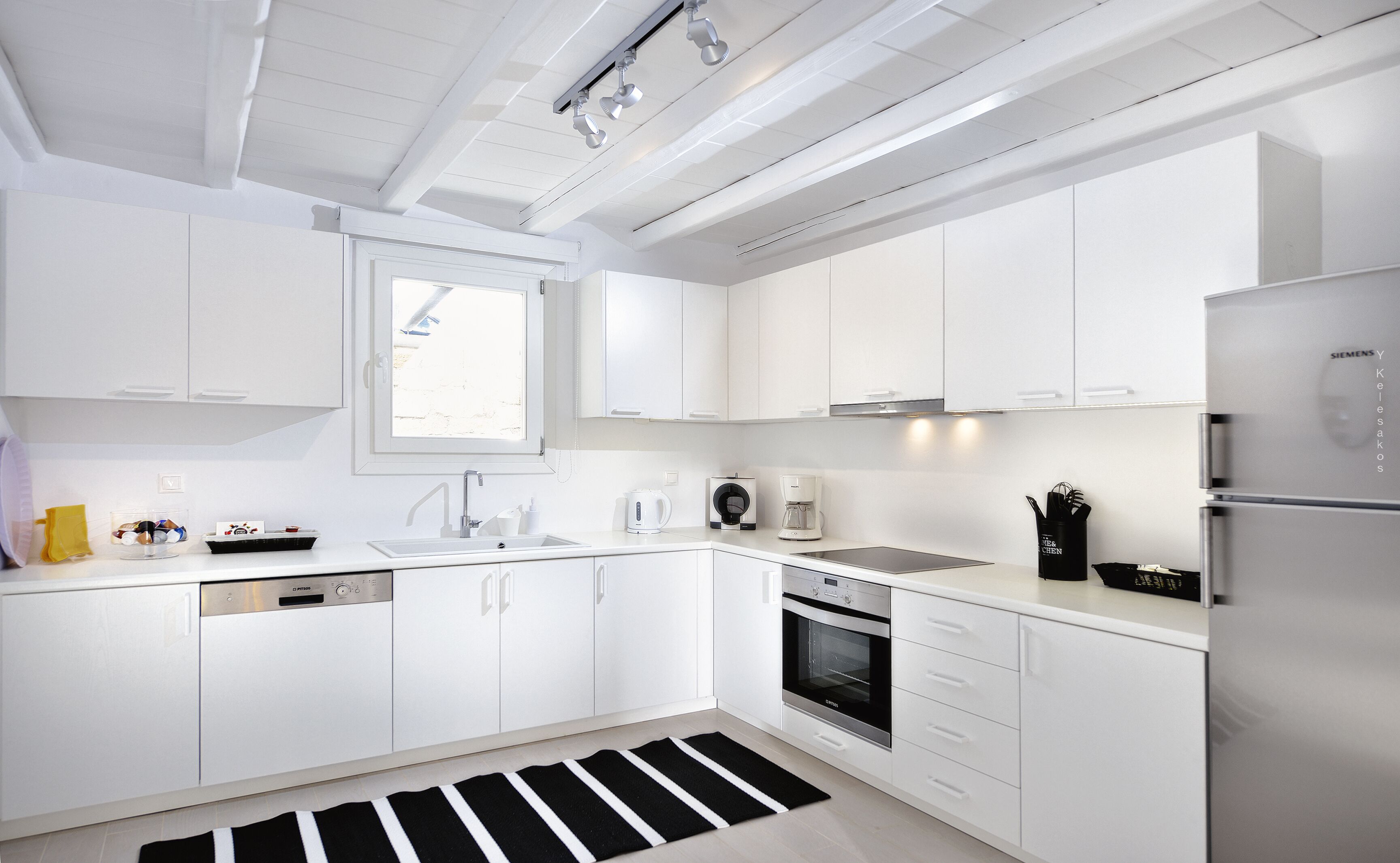 A modern kitchen with white cabinetry, a built-in oven, and a stainless steel refrigerator.