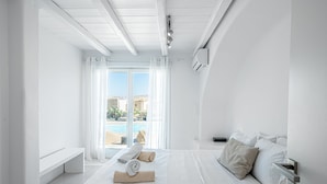 Una moderna camera d'albergo con un ampio letto, una panca e vista su una piscina e edifici.