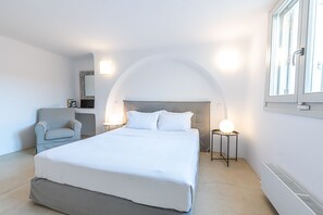 Quarto com uma cama grande, uma cadeira, abajures e uma janela com vista.