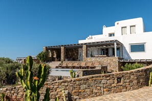 Um edifício moderno branco com um pátio de pedra, área de estar externa e piscina.