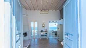 Une pièce avec un plafond en bois, une grande fenêtre donnant sur la mer, une commode avec des tiroirs et un banc.